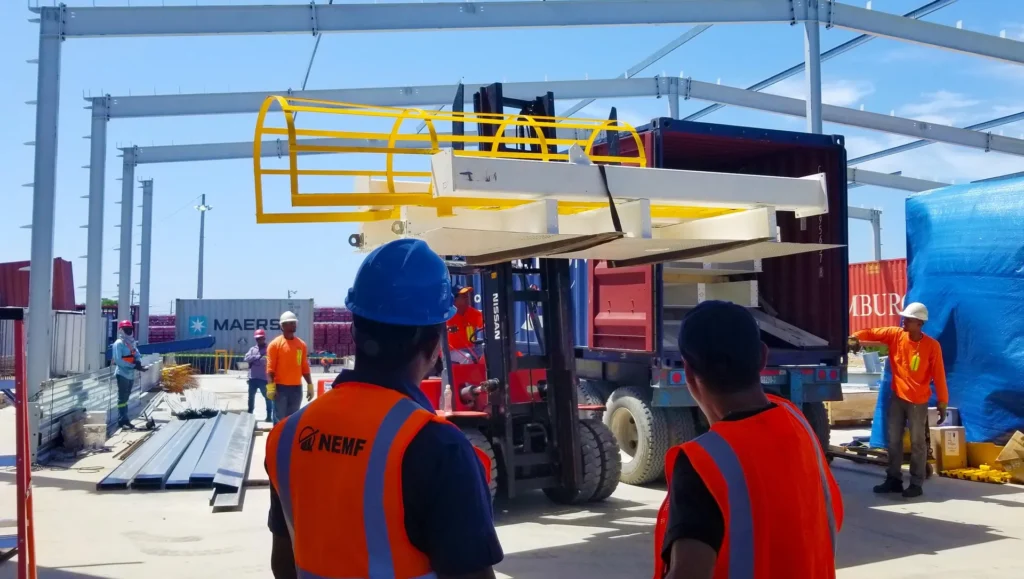 Equipo de NEMF descargando estructura metálica con montacargas